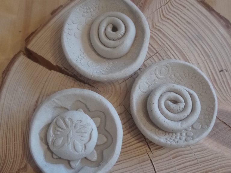 Drei dekorative, helle Tonplatten mit spiralförmigen und blumenförmigen Mustern.